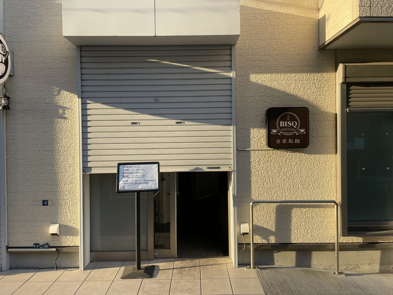 麺屋BISQ（ビスク）店頭。シャッター前に案内ボードが置かれています