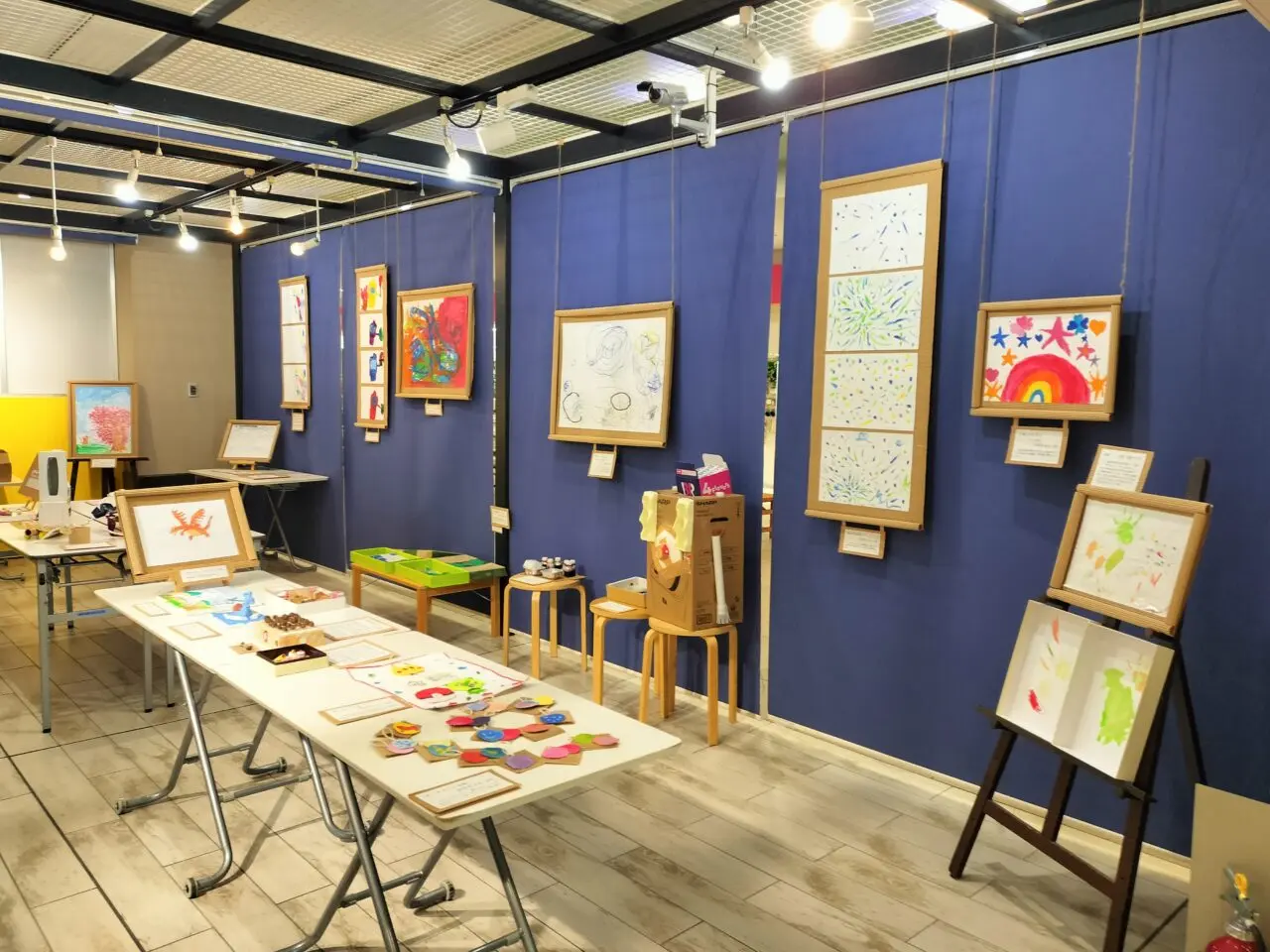 青い壁面に飾られた子どもたちの絵画作品